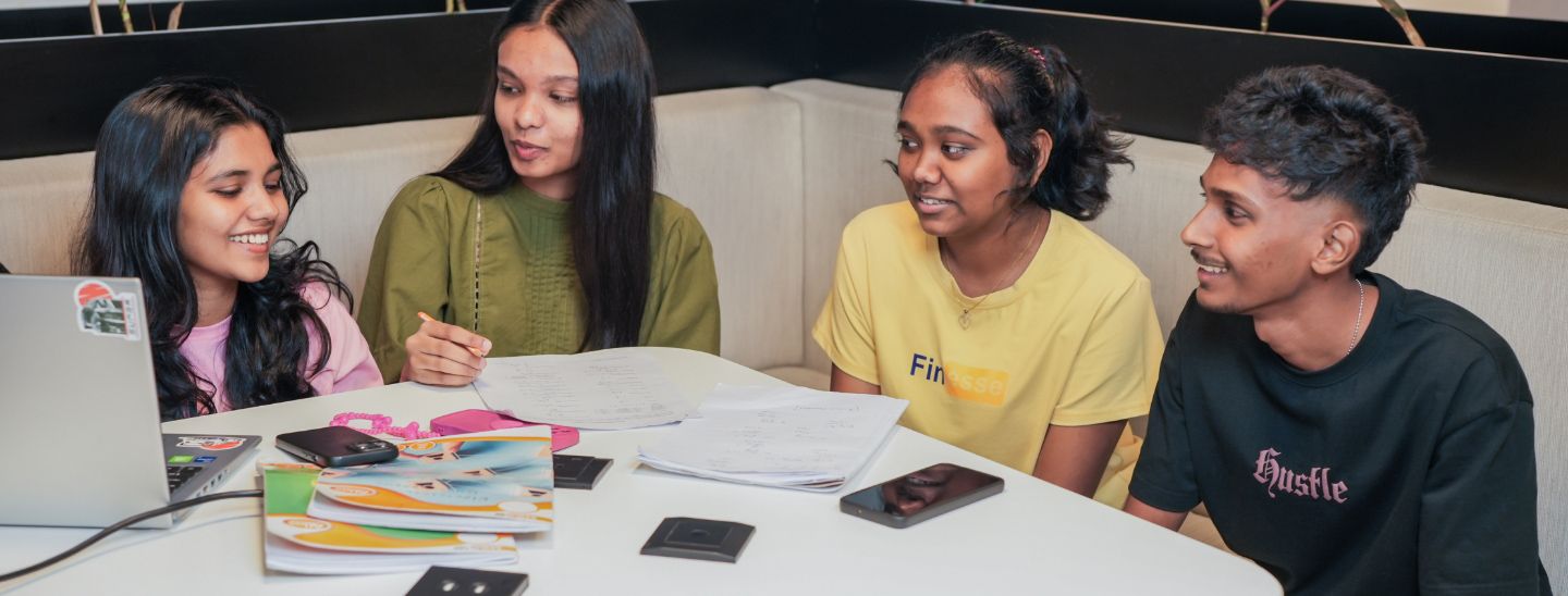 Female student writing on notebook and other students smiling